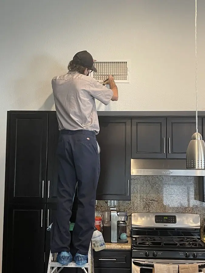 Technician inspecting an air vent during HVAC service in Golden